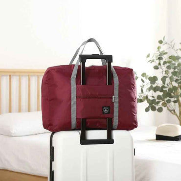 Red foldable travel duffel bag with carry handles and front zip pocket.