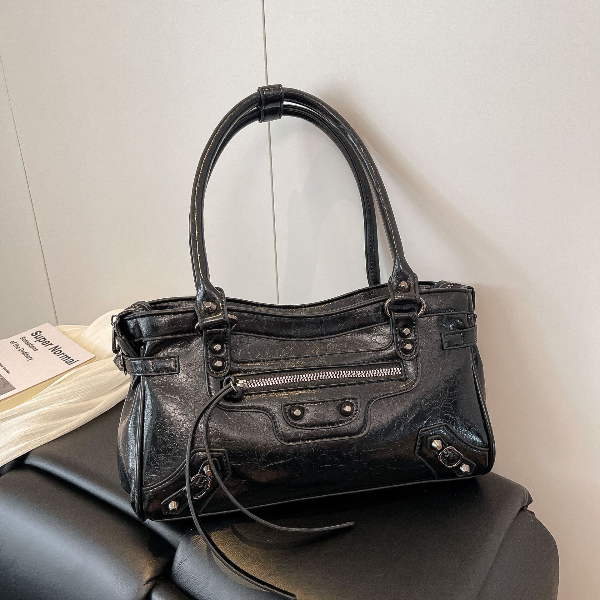 Black leather handbag on a black surface with a light gray wall background