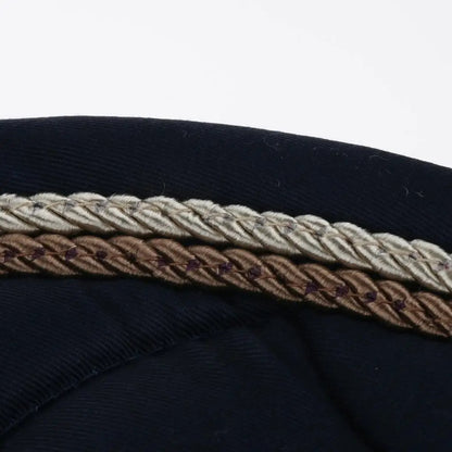 Close-up of a navy blue fabric with a braided trim featuring brown, beige, and white colors.