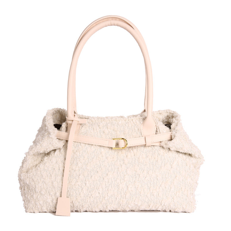 Handbag with beige textured body and pink handle on a white background