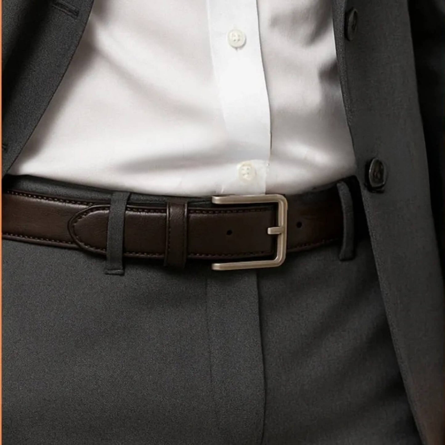 Close-up of a person wearing a brown belt with a gray suit and white shirt.