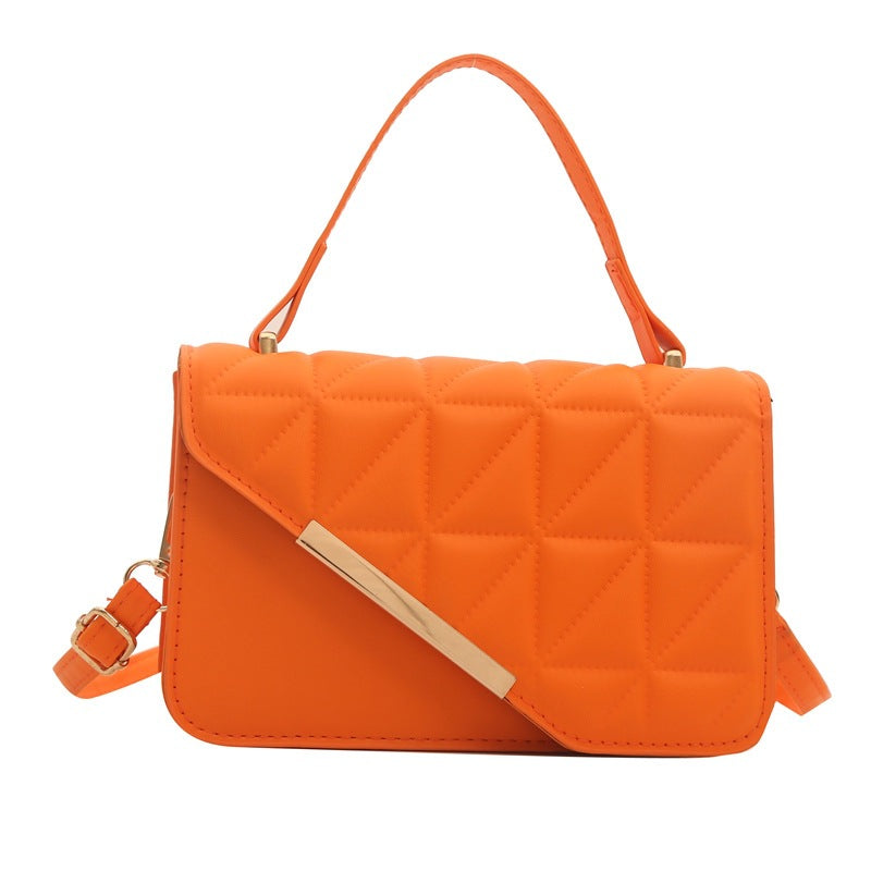 Orange quilted handbag with a strap on a white background