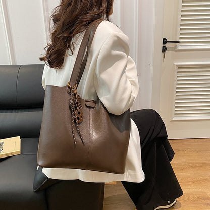 Person holding a brown leather handbag in a room with a couch and door.