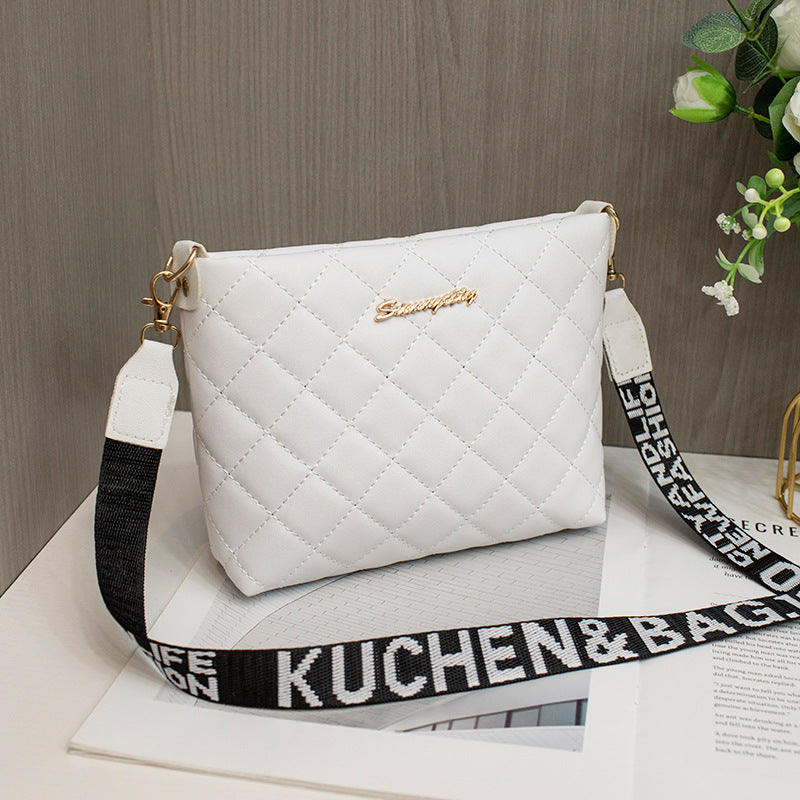 White diamond grid shoulder bag with wide printed shoulder strap and zip closure.