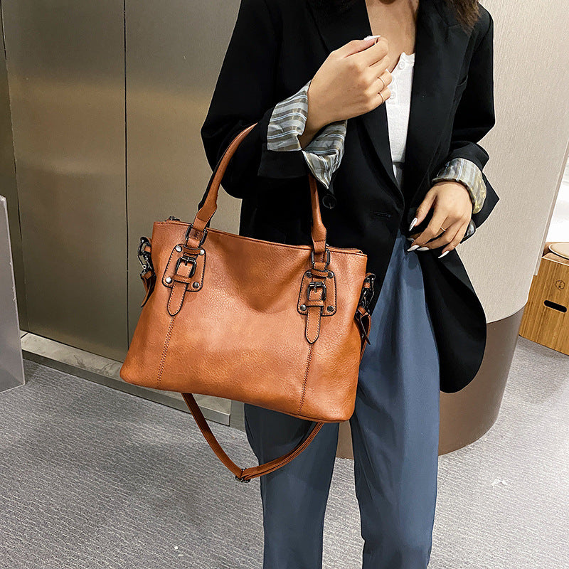 Woman carrying a vintage PU leather tote bag with shoulder strap.